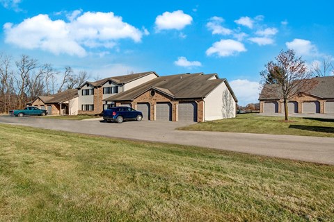 A welcoming exterior here at River’s Cove featuring attached garages, open green space, and a well-maintained setting, creating a quiet, spacious, and inviting community atmosphere.