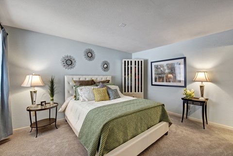 A bedroom with a large bed and two lamps.