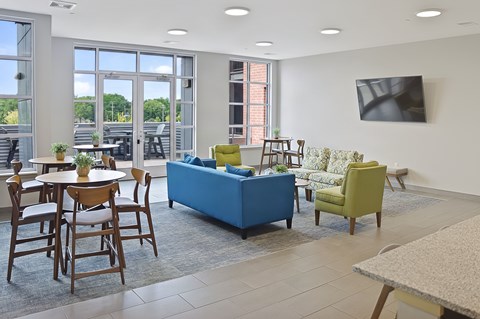 A living room with a blue sofa and a television on the wall.