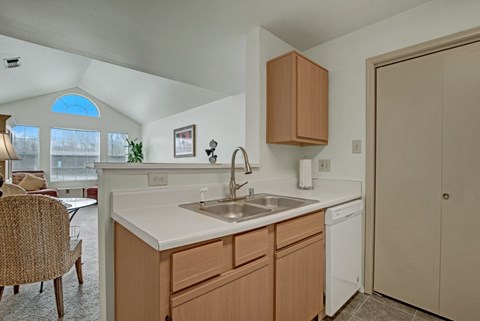 A kitchen with a white counter top and wooden cabinets.