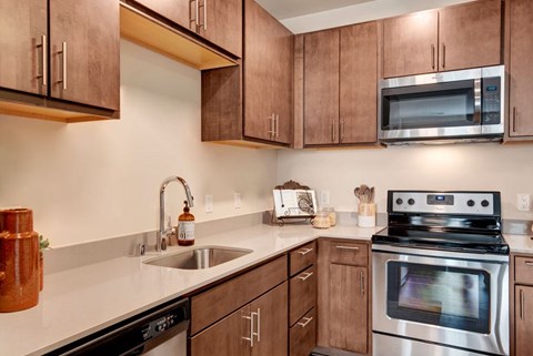 A kitchen with a stove, sink, and cabinets.
