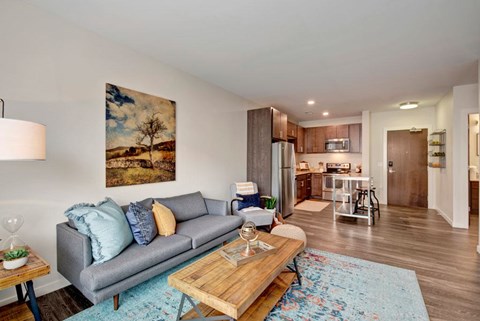 A living room with a grey couch and a painting on the wall.
