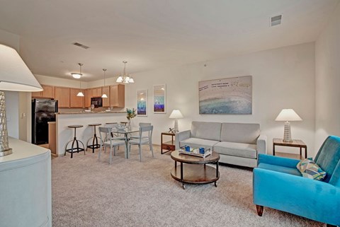 A living room with a blue chair and a grey couch.