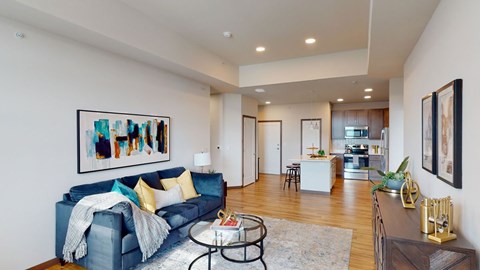 A living room with a blue couch and a painting on the wall.