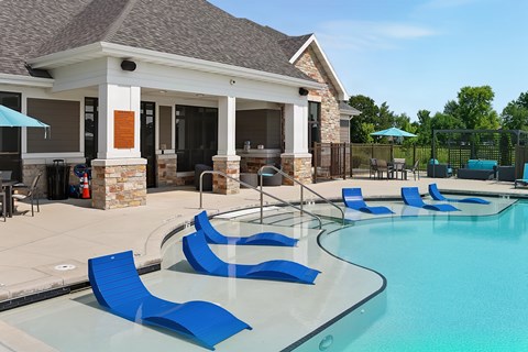 A pool with blue chairs and a house in the background.