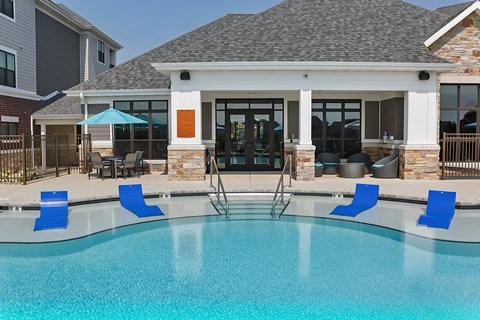 A pool with blue chairs and a building in the background.