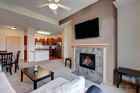A living room with a fireplace and a television mounted above it.