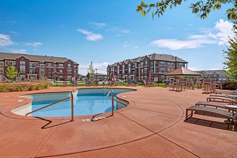 A resort-style outdoor pool here at Van Buren Place with a spacious sundeck and comfortable lounge seating. A shaded patio area and surrounding apartment buildings create a bright, relaxing atmosphere for residents to enjoy.