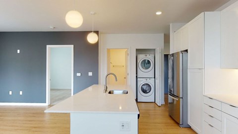 A kitchen with a white counter top and a washer and dryer in the background.