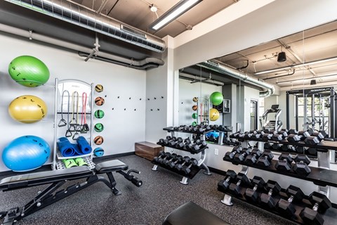 A gym with a variety of equipment including dumbbells, exercise balls, and resistance bands.