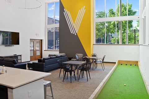 A room with a miniature golf course and a couch.
