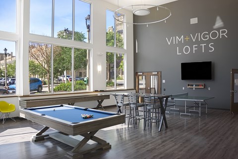 A pool table is in the middle of a room with a glass table and chairs.