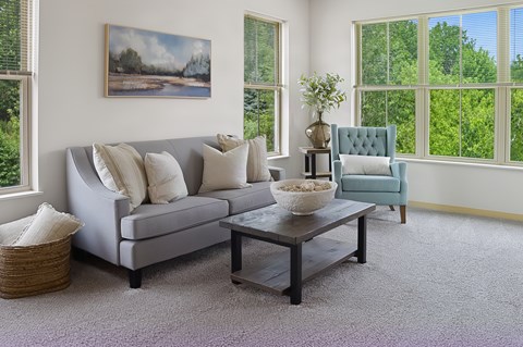 A living room with a grey couch, a coffee table, and a painting on the wall.