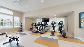 a gym with cardio equipment and a flat screen tv