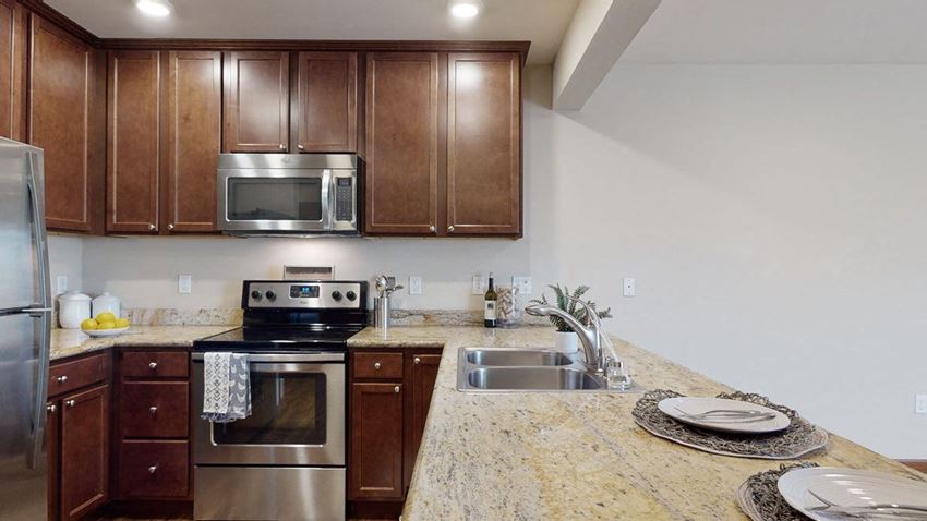 a kitchen with wooden cabinets and stainless steel appliances - Photo Gallery
