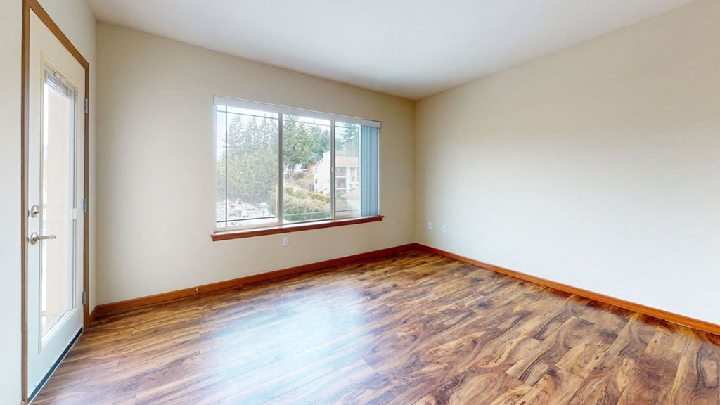 a bedroom with hardwood floors and a large window