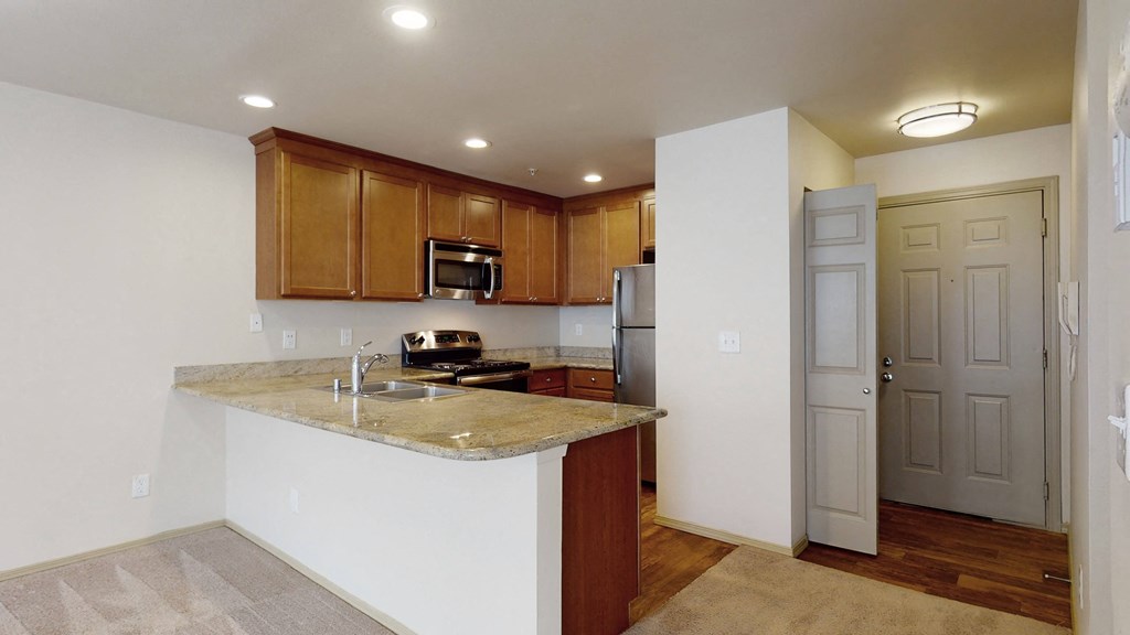 A kitchen with a marble countertop and wooden cabinets.