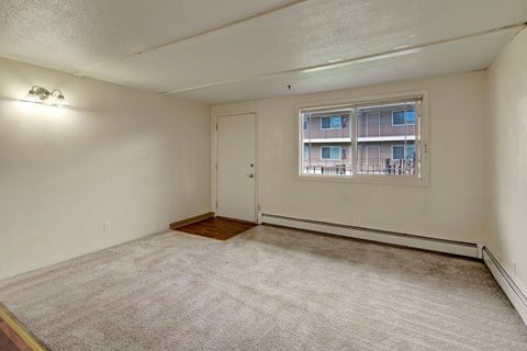 the living room of an apartment with a window and carpet
