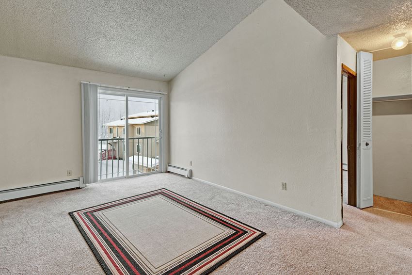 A living room with a sliding glass door out to a private balcony Conifer Grove Apartments - Living Room