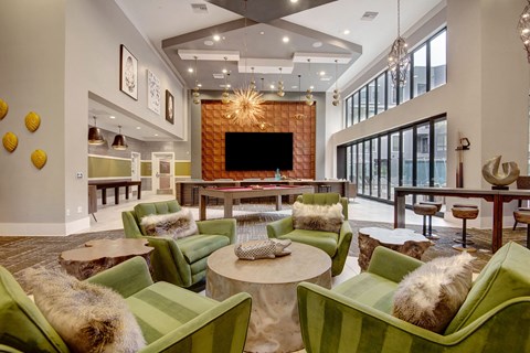 Stylish resident lounge here at Park on Central Apartments with green chairs, fur cushions, round tables, and a pool table. Large windows and modern lighting create a cozy, upscale vibe.
