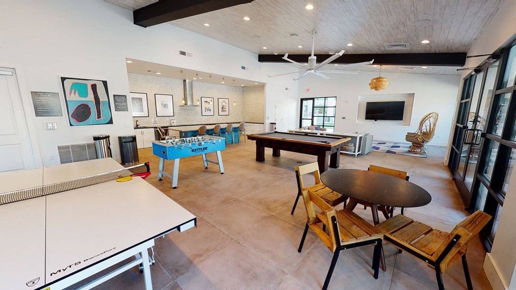Roosevelt Row Resident Lounge Spacious recreational room here at Roosevelt Row Apartments featuring a ping pong table, blue foosball table, pool table, and wicker chair near a wall-mounted TV. Atmosphere is inviting.