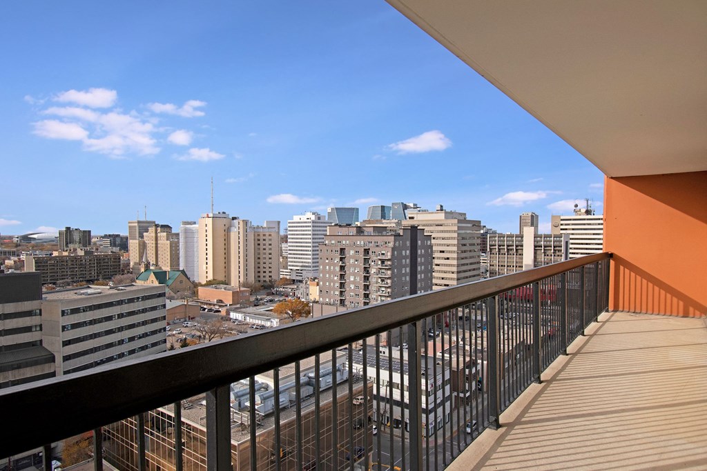 View from a balcony here at Centre Pointe Plaza Apartment Homes overlooking a cityscape with modern buildings and a church. The sky is clear blue, conveying a calm, urban atmosphere.