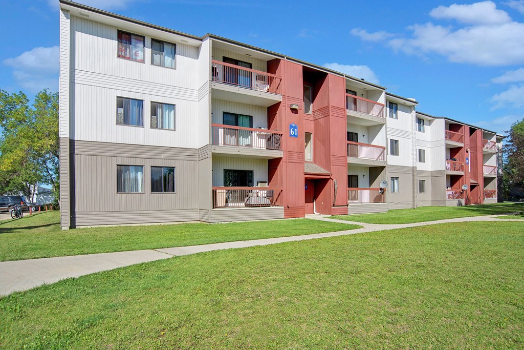 The exterior of the building surrounded by trees and grass Madison Park Apartment Homes Exterior Apartments for rent in Regina, SK