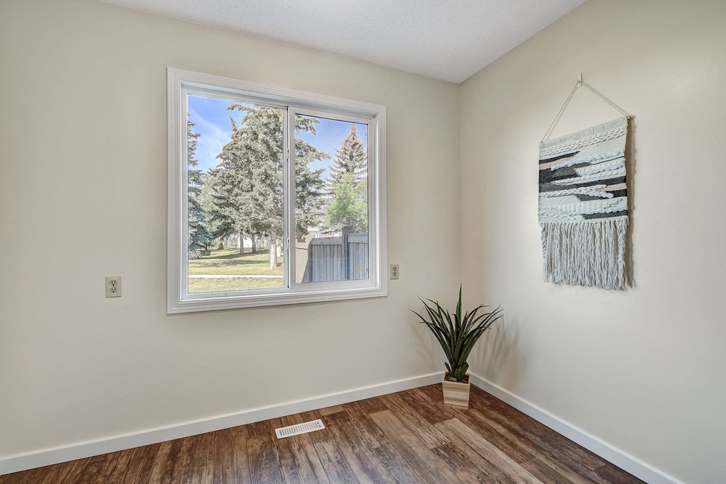a bedroom with a large window and a plant on the floor