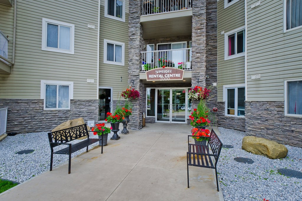 Somerset Pointe Apartment Homes Entrance of Somerset Rental Centre features stone accents, elegant benches, vibrant red and white flowers for a welcoming, inviting atmosphere.
