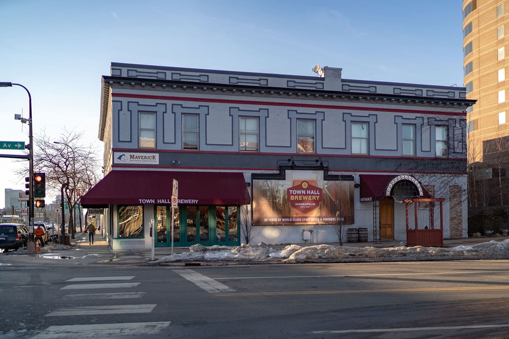 Street view of a grey, two-story building with "Town Hall Brewery" awning and sign near 7west Apartment Homes. Snow on the sidewalk, bare trees, and a clear sky.