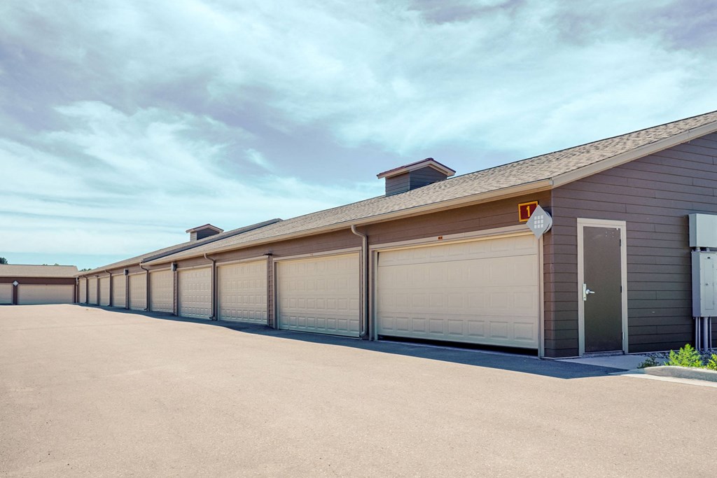 Row of beige garages here at Dakota Ridge Apartment Homes in a clean, empty lot under a clear blue sky. The scene is calm and orderly, with a modern, suburban feel.
