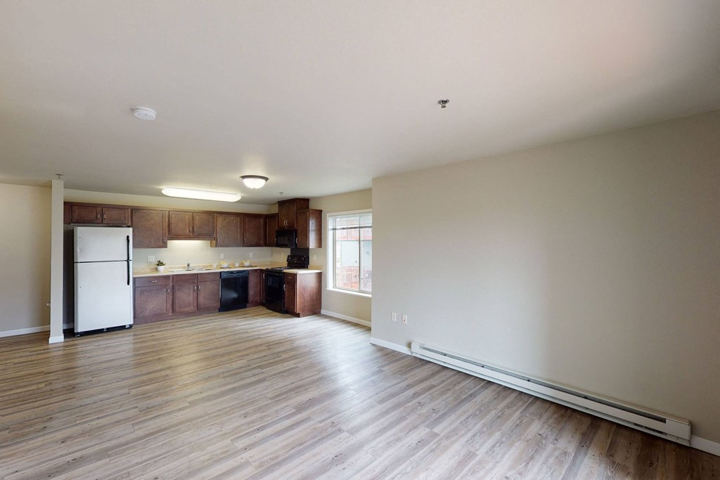 Spacious, modern apartment here at Renaissance Heights Apartment Homes with wood flooring and open floor plan. Kitchen features dark wood cabinets and stainless steel appliances. Bright, neutral tones.