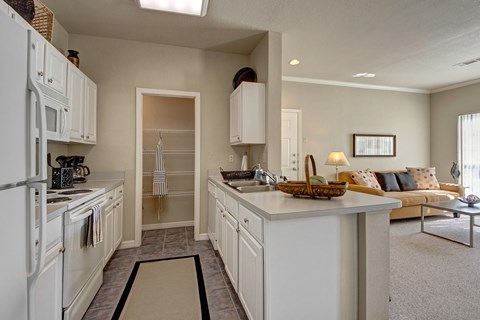 a kitchen with white cabinets and appliances and a living room with a couch