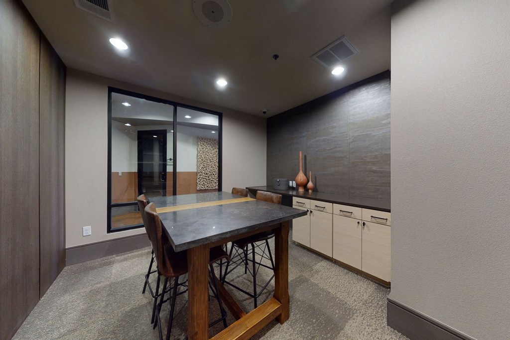 A small, modern meeting room here at Sorrel Fairview Apartment Homes with a dark wooden table, several chairs, and decorative vases on a side cabinet. The room has a calm, professional tone.