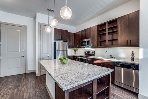 The Crosby at The Brickyard modern kitchen with granite countertops and wooden floors Apartments near DFW