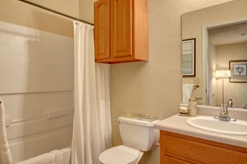 A bathroom with a tub, wall storage, and wide mirror over the sink Residence at Heritage Park Bathroom Abilene Apartments - Photo Gallery 3