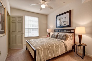 A cozy bedroom with ceiling fan and window overlooking the property Residence at Heritage Park Bedroom Apartments in Abilene - Photo Gallery 4