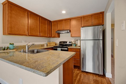 a kitchen with a granite counter top and stainless steel refrigerator