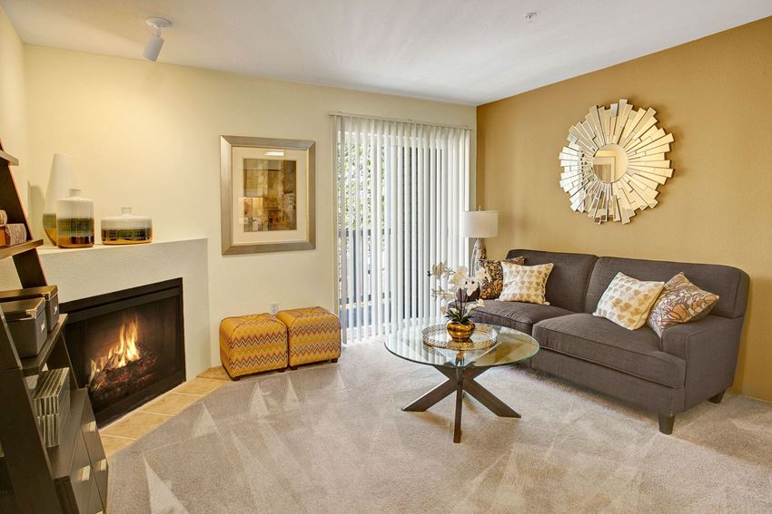 Living room with couch, coffee table, fireplace, and sliding glass door leading out to the balcony Allegro Living Room Apartments in Covington, WA - Photo Gallery