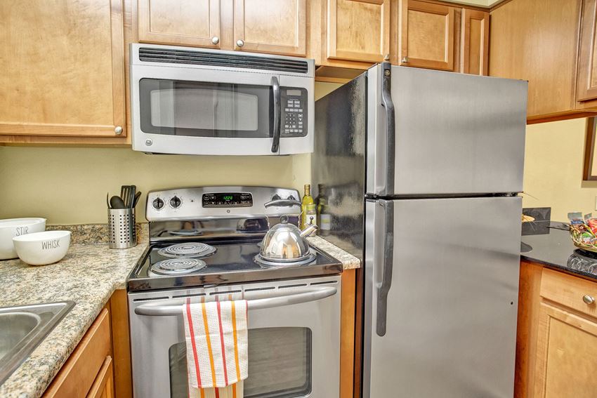 Colonial Square kitchen featuring stove, oven, microwave, sink,and refrigerator with lots of cabinet storage Colonial Square Kitchen Apartments in Bellevue, WA