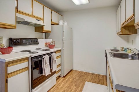 a kitchen with white appliances and wood flooring and a refrigerator
