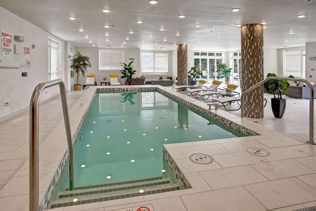 Indoor pool with lounge chairs and couches Heritage Hill Indoor Pool Apartments in Renton, WA