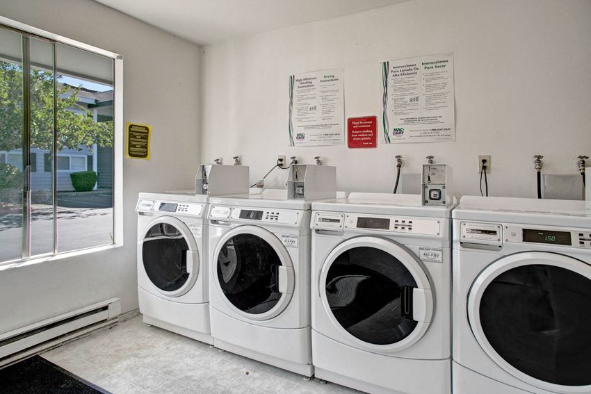 A shared laundry room with multiple coin operated washers and dryers Lake Park Laundry Apartments in Everett, WA