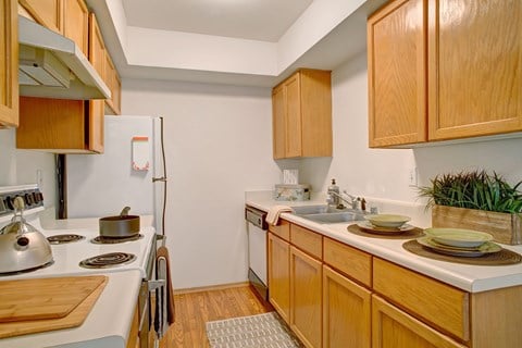 a kitchen with white appliances and wooden cabinets and a sink