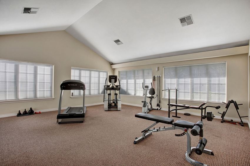 A large gym with a treadmill, elliptical, bike, and weights Lion's Gate Gym