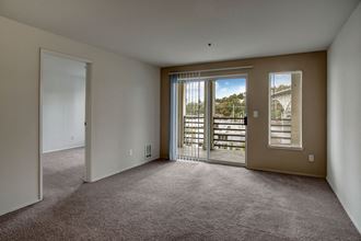 Living room with wall to wall carpeting and large sliding glass doors leading out to the private balcony St James Tower Living Room Apartments in Seattle, WA