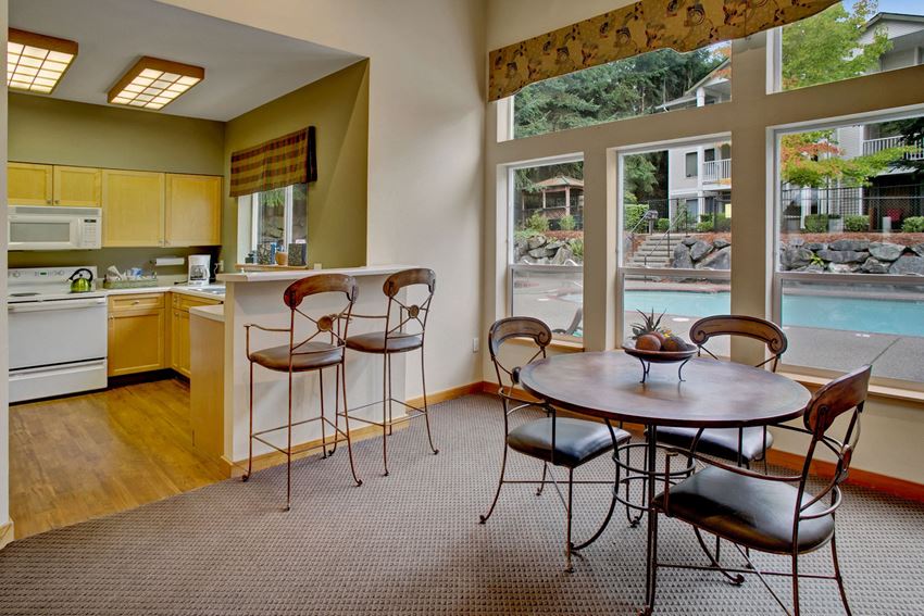 A shared space for residents with tables, chairs, and a large kitchen with a view over the outdoor pool Sunrise Lane Resident Lounge Apartments in Everett, WA - Photo Gallery