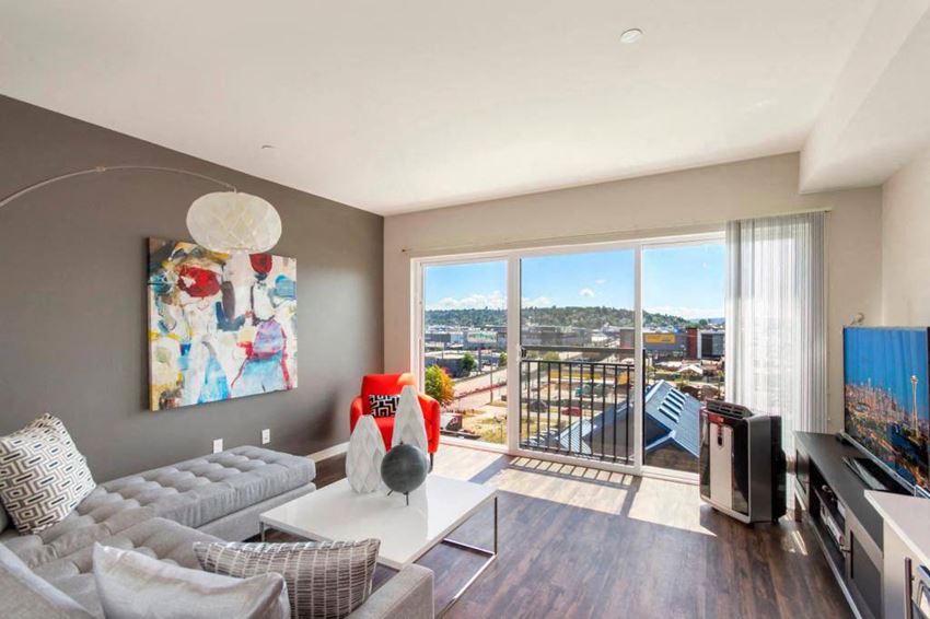 A spacious living room with large windows and a sliding glass door leadnig out to the Juliet balcony Vive Living Room Apartments in Seattle, WA - Photo Gallery