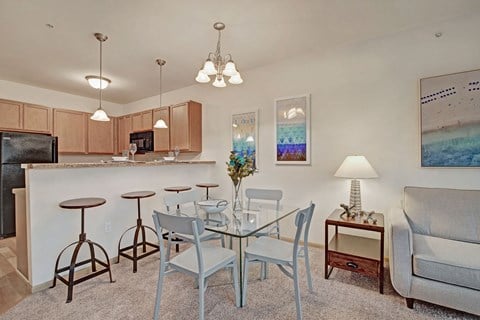 a dining area with a glass table and chairs and a living room with a kitchen
