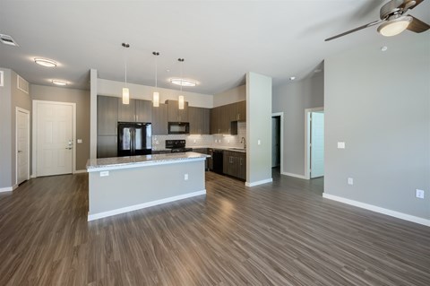 A spacious kitchen with a bar counter and a ceiling fan.